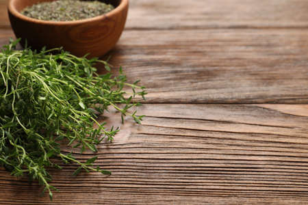 Bowl with dried thyme and fresh herb on wooden table. Space for textの写真素材