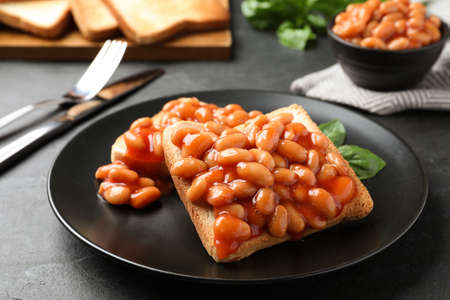Toasts with delicious canned beans on black tableの写真素材