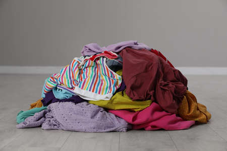 Pile of dirty clothes on floor near gray wall indoors