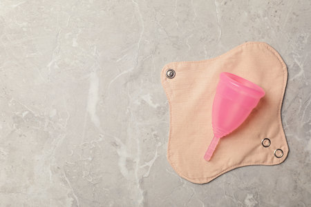 Menstrual cup and cloth pad on gray background, top view. Space for textの写真素材