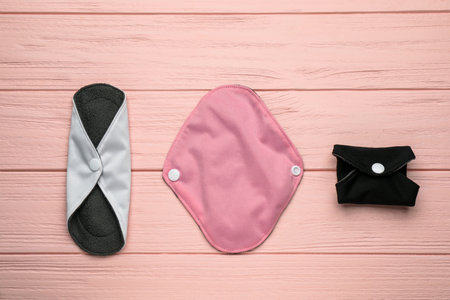 Many reusable cloth menstrual pads on pink wooden table, flat layの写真素材