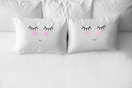 Soft pillows with cute faces on comfortable bed, above viewの写真素材