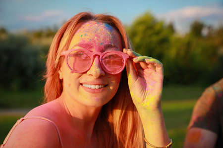 Happy woman covered with colorful powder dyes outdoors. Holi festival celebration