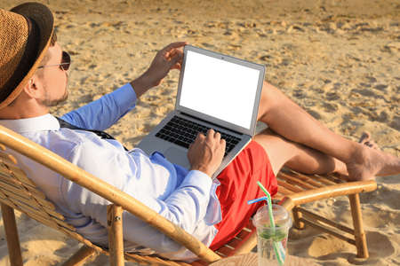Man with laptop sitting on sandy beach. Business tripの写真素材