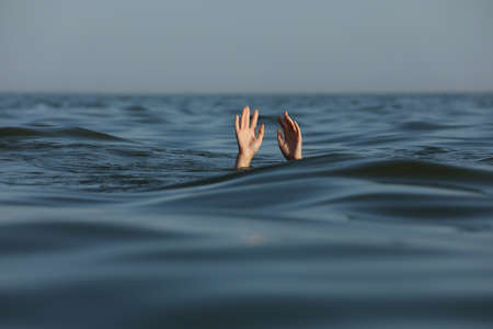 Drowning woman reaching for help in seaの写真素材