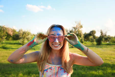 Happy woman covered with colorful powder dyes outdoors. Holi festival celebration