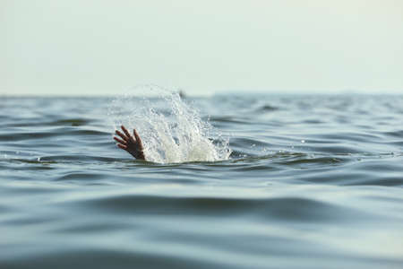 Drowning woman reaching for help in sea