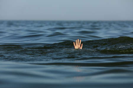 Drowning woman reaching for help in seaの写真素材