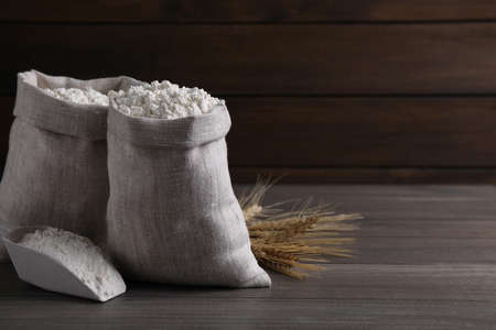 Sacks with flour and wheat spikes on wooden background. Space for textの写真素材