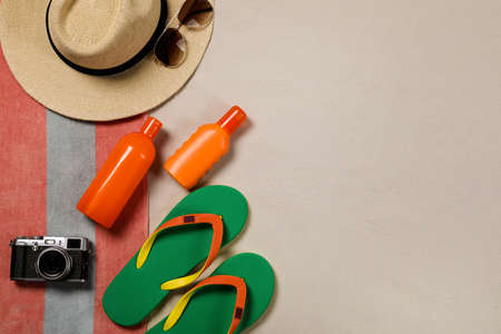 Beach towel, hat, sunglasses, camera, sunscreen and flip flops on sand, flat lay. Space for textの写真素材