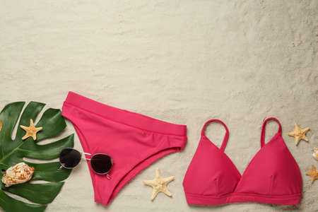 Stylish bikini and beach accessories on sand, flat lay. Space for textの写真素材