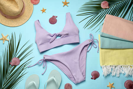 Beach towel, swimsuit, hat and flip flops on light blue background, flat layの写真素材