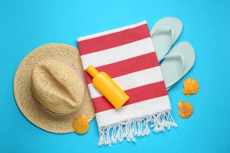 Beach towel, flip flops, hat and sun protection product on light blue background, flat layの写真素材