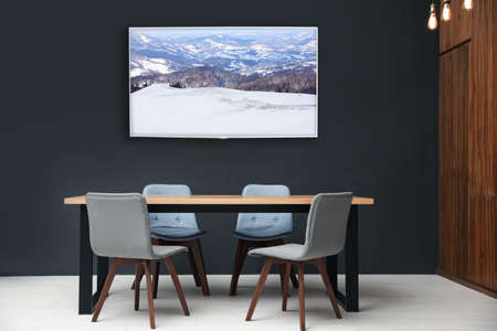 Modern wide screen TV on black wall in room with stylish furnitureの写真素材