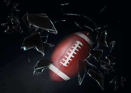 American football ball breaking up glass against black background