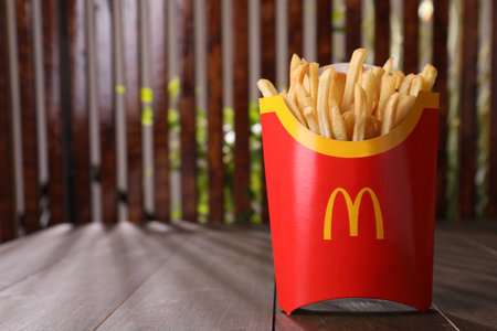 MYKOLAIV, UKRAINE - AUGUST 12, 2021: Big portion of McDonald's French fries on wooden table. Space...