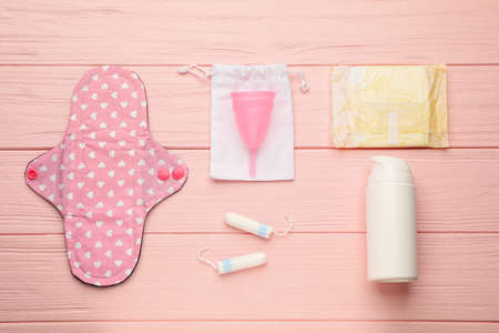 Cloth menstrual pad and other female hygiene products on pink wooden table, flat layの写真素材
