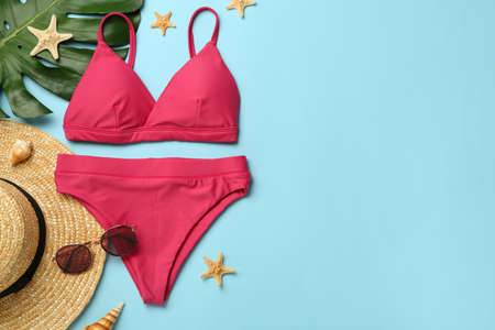 Stylish bikini and beach accessories on light blue background, flat lay. Space for textの写真素材