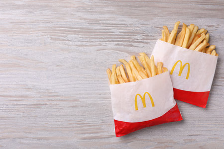 MYKOLAIV, UKRAINE - AUGUST 12, 2021: Two small portions of McDonald's French fries on white wooden...