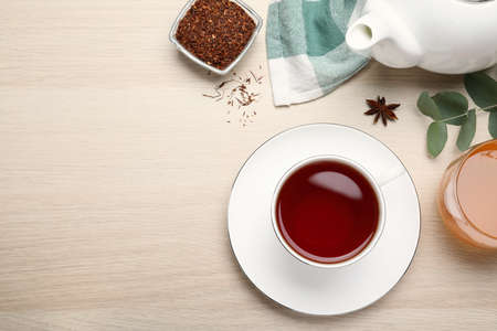 Freshly brewed rooibos tea, dry leaves, honey and anise on white wooden table, flat lay. Space for textの写真素材