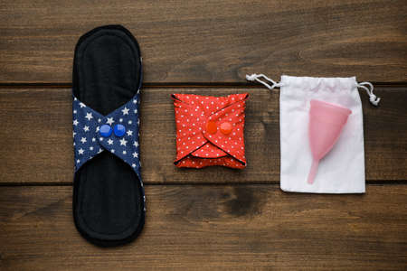 Reusable cloth pads and menstrual cup on wooden table, flat layの写真素材