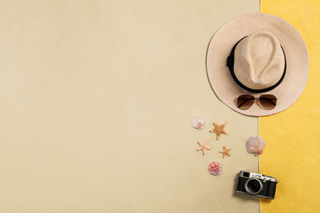 Beach towel, hat, sunglasses, camera, starfishes and sea shells on sand, flat lay. Space for textの写真素材