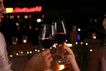 Romantic couple with glasses of red wine on cafe terrace at night, closeupの写真素材