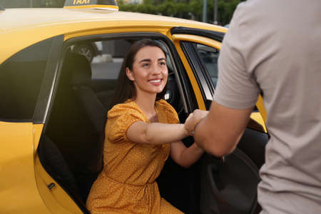 Man helping young woman to get out of taxi outdoorsの写真素材