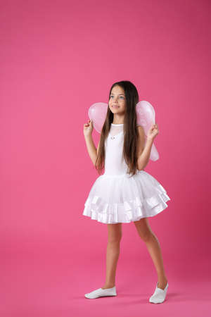 Cute little girl in fairy costume with white wings on pink backgroundの写真素材