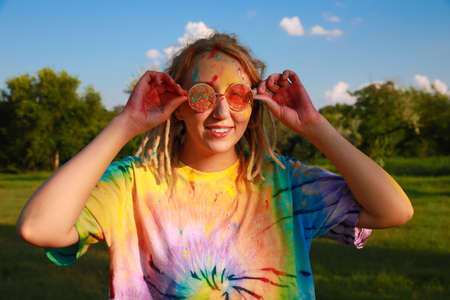 Happy woman covered with colorful powder dyes outdoors. Holi festival celebrationの写真素材