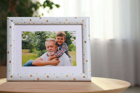 Framed family photo on wooden table in room. Space for text