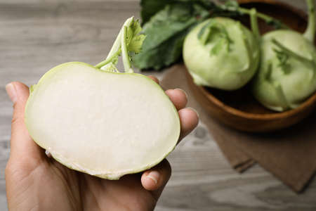 Woman holding half of kohlrabi plant at table, closeupの写真素材