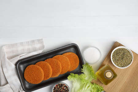 Uncooked breaded cutlets on white wooden table, flat lay. Freshly frozen semi-finished productの写真素材