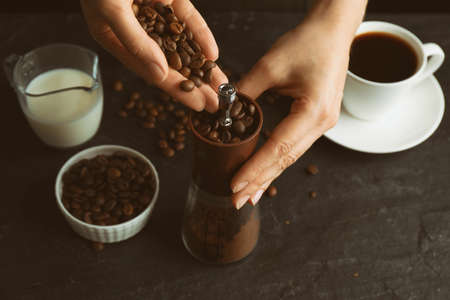Woman using manual coffee grinder at black table, closeupの写真素材