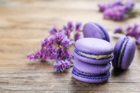 Delicious purple macarons and lilac flowers on wooden table, space for textの写真素材