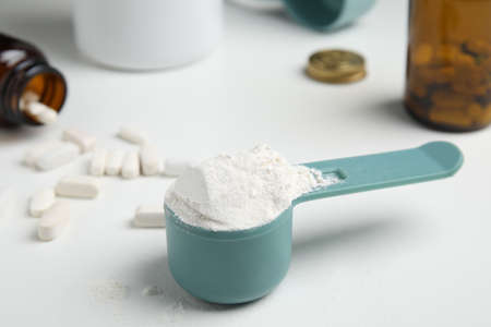 Measuring scoop of amino acids powder on white tableの写真素材