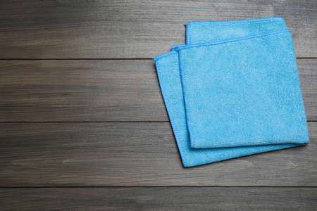 Light blue microfiber cloth on wooden table, top view. Space for text