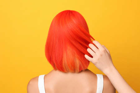 Professional stylist and young woman with bright dyed hair on orange background, back viewの写真素材