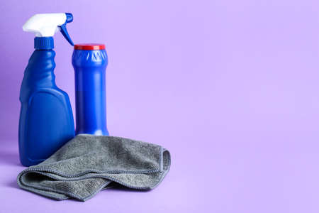 Gray microfiber cloth and detergents on light background, space for text