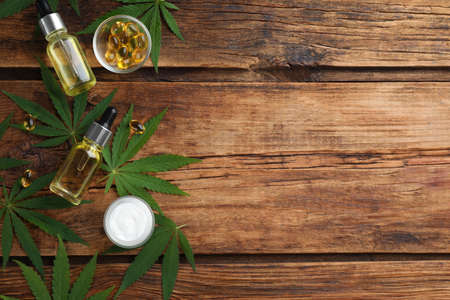 Composition with CBD oil, THC tincture and hemp leaves on wooden table, flat lay. Space for textの写真素材