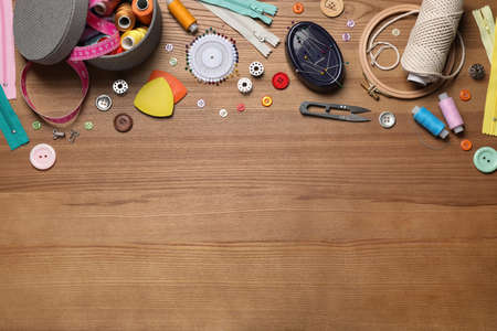 Flat lay composition with different sewing accessories on wooden background. Space for textの写真素材