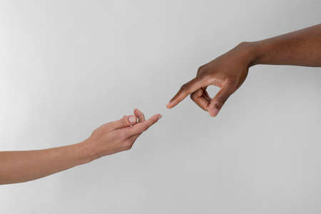 Woman and African American man touching fingers on light gray background, closeupの写真素材