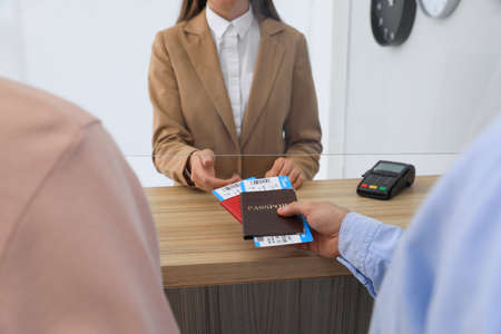 Man giving passports with tickets to agent at check-in desk in airport, closeup