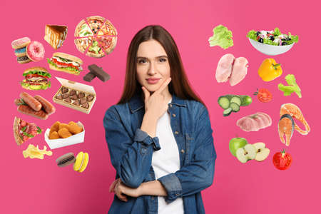 Doubtful woman choosing between healthy and unhealthy food on pink backgroundの写真素材