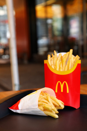 MYKOLAIV, UKRAINE - AUGUST 11, 2021: Big and small portions of McDonald's French fries on tray in cafeのeditorial素材