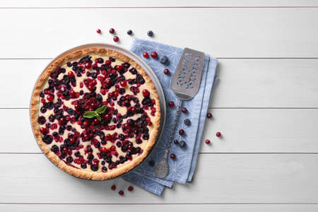 Delicious currant pie and fresh berries on white wooden table, flat layの写真素材