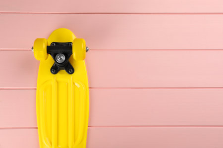 Yellow skateboard on pink wooden background, top view. Space for textの写真素材