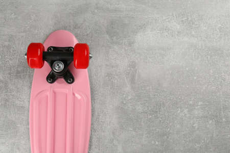 Pink skateboard on gray stone background, top view. Space for textの写真素材