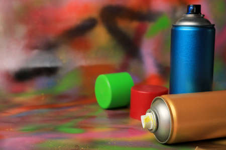 Cans of different graffiti spray paints on color background, closeup. Space for textの写真素材