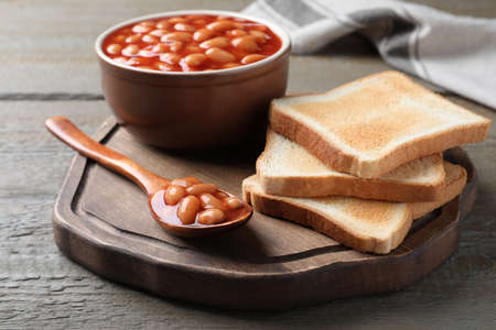 Toasts and delicious canned beans on wooden tableの写真素材